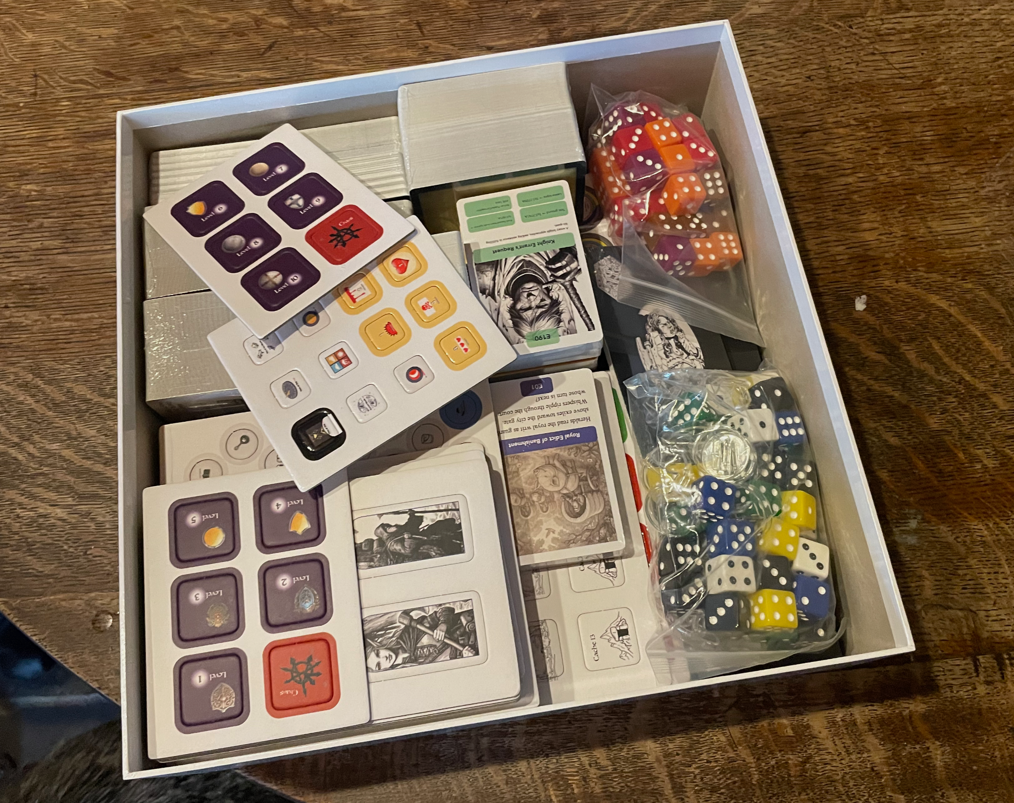Open prototype game box containing cards, tokens, dice and components.